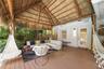 Covered patio featuring a thatched gable roof with exposed log support beams, composite decking, and a wall-mounted light fixture