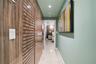 Hallway featuring polished tile flooring, vertical wood-panel wall treatments, louvered built-in cabinet doors, and recessed ceiling lighting