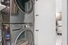 Stacked stainless steel laundry appliances housed within a white cabinetry enclosure