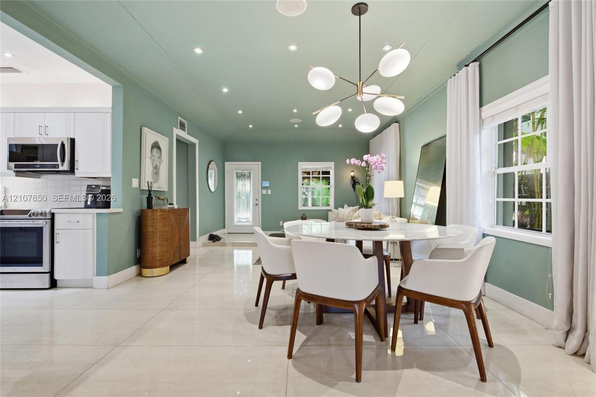 Open-concept living space featuring high-gloss tile flooring, recessed lighting, a modern multi-globe chandelier, and a kitchen equipped with white ca