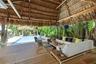 Open-air pavilion featuring a thatched roof, wood-finish decking, and a built-in wall-mounted fan, overlooking an in-ground swimming pool