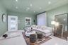 Living area featuring large-format tile flooring, tray ceiling, recessed lighting, and an exterior door with integrated decorative glass panels