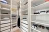 Custom closet system featuring white built-in shelving, adjustable storage racks, integrated cabinetry, and multi-tier drawer units