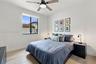 Neutral-toned walls, wood-finish flooring, a contemporary ceiling fan with integrated lighting, and a window with a dark-finish frame