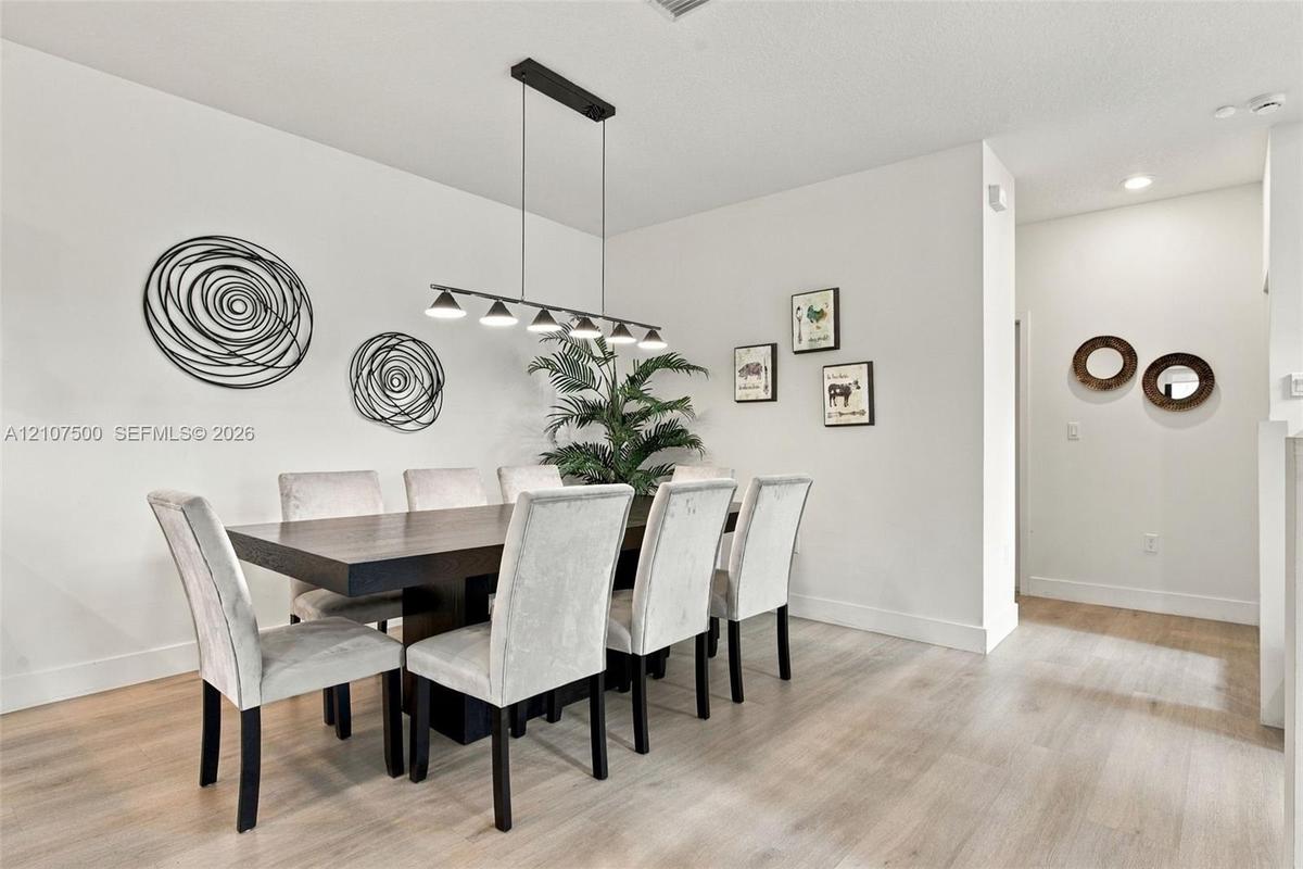 Neutral wall color palette, light-toned wood-finish flooring, and a linear multi-light pendant fixture