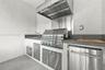 Outdoor kitchen featuring stainless steel built-in grill, professional-grade range hood, stone-finish countertops, stainless steel under-counter cabin