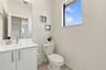 White vanity featuring a rectangular integrated sink, chrome faucet, and vertical pulls, paired with an expansive wall-mounted mirror and a window
