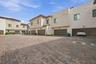 Multi-unit exterior featuring stucco siding, tile roof accents, paved brick driveway, and integrated garage parking