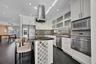 Kitchen featuring white shaker cabinetry, stainless steel appliances, built-in wine rack, stone countertops, and recessed lighting