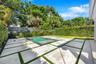Backyard featuring a swimming pool, concrete paver hardscaping with turf ribbons, perimeter privacy fencing, and mature landscaping