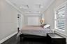 Tray ceiling with recessed lighting, dark wood-finish flooring, white plantation shutters, and double-door closet cabinetry