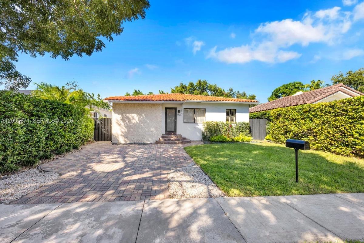 Exterior featuring a stucco facade, clay tile roof, paver driveway, and manicured landscaping