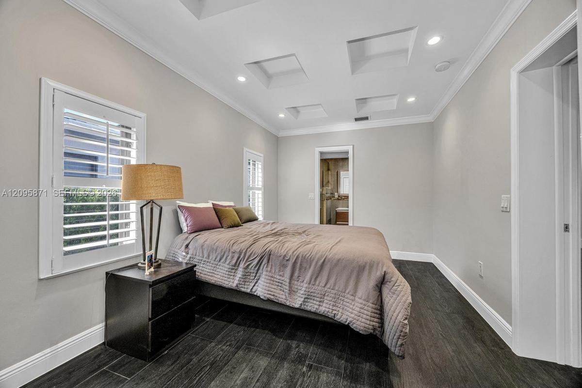 Coffered ceiling featuring recessed lighting, white plantation shutters, and dark wood-finish tile flooring