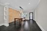 Textured stone accent wall, multi-pendant light fixture, wood-finish flooring, built-in display shelving, and plantation shutters