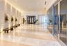 Grand lobby featuring a textured stone accent wall, large-format tile flooring, recessed ceiling lighting, and a curved floor-to-ceiling glass wall en
