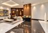 Polished stone flooring with contrasting inlay patterns, tray ceiling with recessed lighting, and wood-paneled accent wall featuring integrated displa