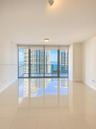 Floor-to-ceiling glass windows, ceramic tile flooring, and a glass-paneled balcony with panoramic water and skyline scenery