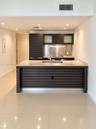 Kitchen featuring dark wood-finish cabinetry with horizontal slat detailing, stone-surface island countertop, integrated stainless steel backsplash, a