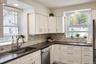 Kitchen featuring shaker-style cabinetry, dark solid-surface countertops, subway tile backsplash, stainless steel appliances, and dual windows