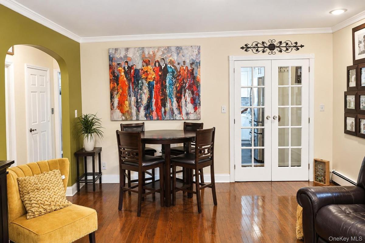 Wood-finish flooring, architectural arched opening, and glass-paned double French doors with white casing