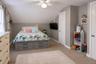 Neutral-toned bedroom featuring angled ceilings, neutral wall-to-wall carpeting, and a ceiling-mounted light fixture with integrated fan