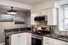Kitchen featuring white Shaker-style cabinetry, dark solid-surface countertops, stainless steel appliances, subway tile backsplash, and a contemporary