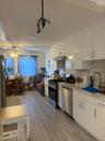Kitchen featuring white gloss cabinetry, stone-finish countertops, stainless steel appliances, and wood-finish flooring