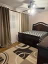 Room featuring wood-finish flooring, crown molding, and a multi-blade ceiling fan with integrated lighting