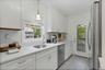 Kitchen with appliances with stainless steel finishes, pendant lighting, light stone counters, white cabinets