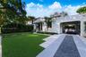 Stucco exterior featuring a tiled roof, arched carport, paved driveway with gravel center inlay, and manicured front lawn