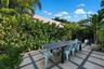 Rear patio featuring large-format stone pavers, geometric gravel inlay, and established perimeter hedges