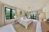 Neutral interior featuring large-format tile flooring, recessed lighting, a modern multi-tiered chandelier, black-framed windows, and a set of glass-p