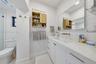 Bathroom featuring a white vanity with integrated double sinks, quartz countertop, brass-tone hardware, wall-mounted faucets, and subway tile wall sur