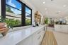 Kitchen featuring white cabinetry with gold-toned hardware, solid-surface countertops, recessed lighting, and black-framed windows