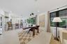 Open-concept kitchen and dining area featuring white shaker-style cabinetry, a central island with bar seating, large-format tile flooring, and oversi