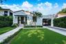 Stucco exterior featuring a clay tile roof, arched carport, private walkway, and mature landscaping