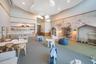 Expansive room featuring a decorative curved ceiling design, integrated cloud-style pendant lighting, built-in lower cabinetry with a horizontal shelv