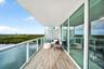 Covered balcony with wood-finish flooring, glass panel railings, and floor-to-ceiling sliding glass doors