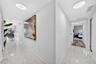 Hallway featuring polished stone-finish tile flooring, recessed LED ceiling lighting, and crisp white wall finishes