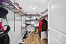 Storage space featuring wood-finish flooring, adjustable metal shelving, and a flush-mount ceiling light fixture
