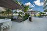 Outdoor kitchen featuring a built-in stainless steel grill and stone-finish countertop beneath a louvered pergola, complemented by large-format tile f