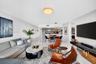 Open-concept living space featuring high-gloss tile flooring, recessed lighting, neutral wall finishes, and integrated cabinetry