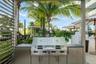 Outdoor kitchen featuring stainless steel cabinetry, a built-in dual-zone grill, and a smooth countertop, sheltered by a metal pergola frame
