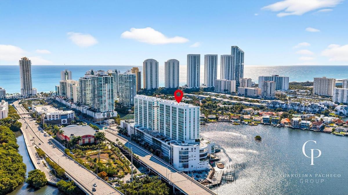High-rise coastal residential building featuring extensive glass-panel balconies, positioned on the waterfront with immediate access to a deep-water c