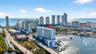 High-rise coastal residential building featuring extensive glass-panel balconies, positioned on the waterfront with immediate access to a deep-water c