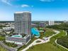 High-rise residential tower featuring a multi-level parking structure, an expansive outdoor pool deck, and proximity to a large coastal lagoon