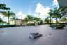 Expansive paved terrace featuring a louvered metal pergola, built-in outdoor kitchen, integrated landscape lighting, and mature palm trees