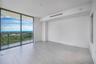 Floor-to-ceiling glass sliding doors, private balcony, neutral large-format tile flooring, and floor-to-ceiling windows with coastal horizon scenery