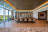 Floor-to-ceiling glass windows, wood-finish ceiling with cove lighting, custom arched built-in shelving, stone-topped bar, and large-format tile floor