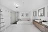 Bathroom featuring a wall-mounted double vanity with wood-finish cabinetry, rectangular vessel sinks, large-format tile flooring, a glass-enclosed wal